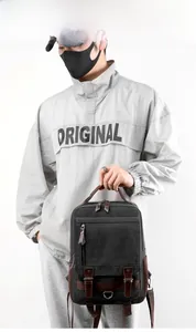 Detail of vintage black canvas backpack showing brown leather straps and metal buckles