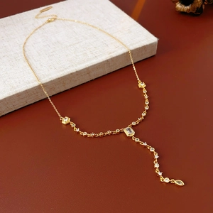 Close-up of golden Y-shaped necklace with oval zircon and tassels on display pad