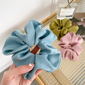 Detailed view of oversized satin scrunchies in blue, green, and pink colors
