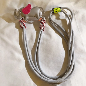 Close-up of a grey braided phone strap with a grey and pink cartoon elephant charm