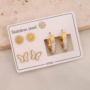 Macro detail of three-pair stainless steel earring set with floral and butterfly designs