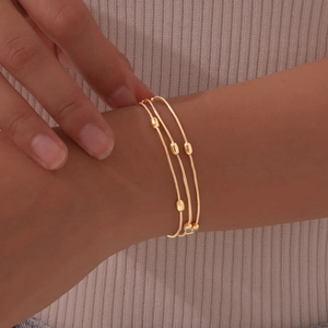 Detailed close-up of a three-layer gold-plated snake chain bracelet with oval beads