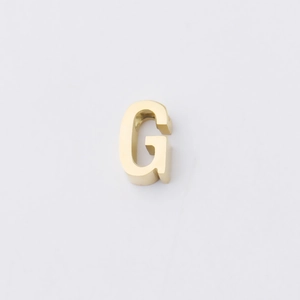 Macro view of polished gold 3D letter G bead with smooth metallic surface detail