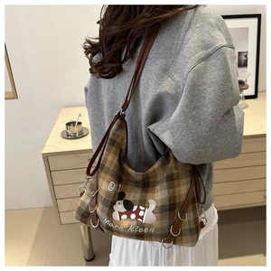 Detail of brown plaid tote with cartoon dog print and leather cord shoulder strap