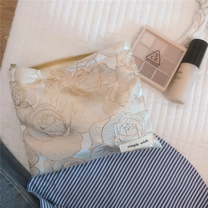 Macro shot of elegant cream-white rose jacquard makeup bag with metal zipper detail