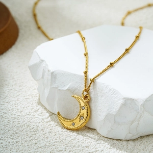 Détail macro du pendentif croissant de lune en or 18K avec zircons sur chaîne satellite