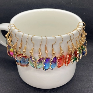 Gradient crystal rectangular and heart earrings hanging on white ceramic cup