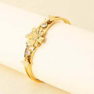 Détail du bracelet doré ouvert avec fleurs, papillons et incrustation de pierres blanches