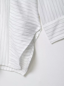 Detail of vertical striped shirt showing side slit and fine stitching on the fabric