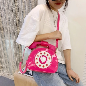 Detail of creative vintage pink phone crossbody bag with handset handle on a model