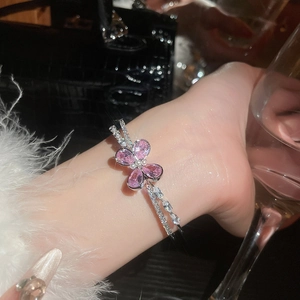 Close-up of silver open bangle featuring pink zircon flower and delicate double-line design