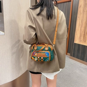 Women's multi-color patchwork crossbody bag with decorative rivets on model in suit