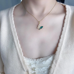 Detail of butterfly necklace featuring green shell wing and sparkling zircon on gold chain