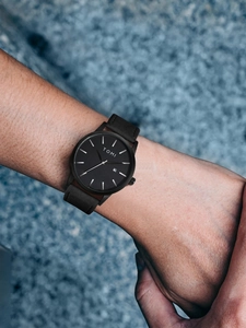 Close-up of minimalist black watch with date display on a person's wrist