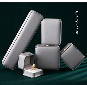 Close-up of luxury grey leather jewelry box set with gold hardware on a textured backdrop