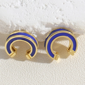 Detailed close-up of blue enamel C-shape ear cuffs with polished golden geometric finish
