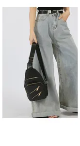 Detail of black matte PU chest bag with adjustable strap and golden zip pockets