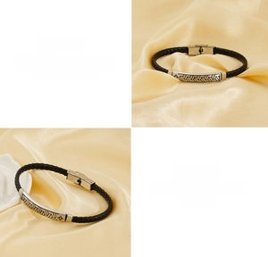 Detail eines geflochtenen schwarzen Lederarmbandes mit gravierter silberner Edelstahlplatte