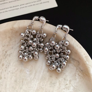 Détail macro de boucles d'oreilles grappes de perles argentées sur marbre