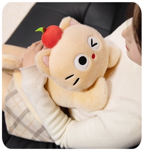 Detailed view of soft yellow cat plush toy with red apple, held for size reference