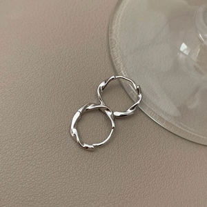 Minimalist s925 silver Mobius hoop earrings in a twisted design on a leather background