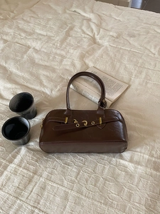 Close-up of vintage brown leather bag with lychee texture and gold buckle details