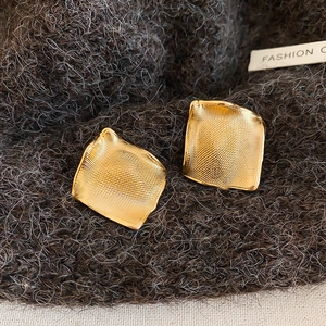 Vue rapprochée de boucles d'oreilles carrées dorées à texture métallique froissée
