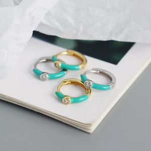 Detail of gold and silver hoop earrings with turquoise enamel and small inset gemstones