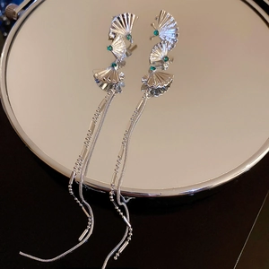 Detail of silver fan-shaped fringe earrings with green gemstone in a mirrored display