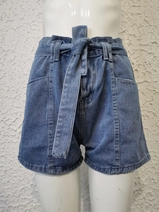 Dettaglio degli shorts in denim a vita alta con cintura annodata e risvolto sulle gambe
