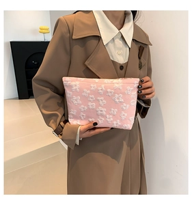 Close-up of pink fabric clutch featuring soft 3D white floral embossed patterns for women