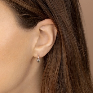 Close-up of gold earrings featuring vibrant rainbow zircons worn on ear for detail