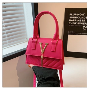 Detail of pink quilted handbag with gold V-logo and tassel held in a stylish setting