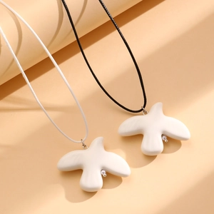 Gros plan de pendentifs oiseaux minimalistes noir et blanc sur colliers en cordon ciré