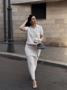 Detail of white knit polo top and long skirt set showing intricate hollow jacquard texture