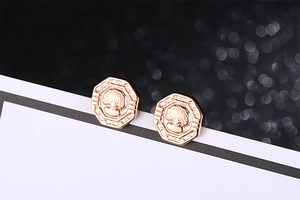 Gros plan de boucles d'oreilles octogonales or rose avec arbre de vie et motifs grecs