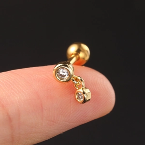 Macro shot of gold stainless steel stud earrings with dual clear zircons on a fingertip