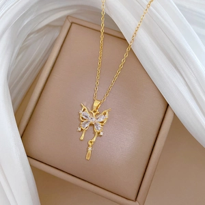 Dettaglio di una collana a farfalla dorata con cristalli su un portagioie beige