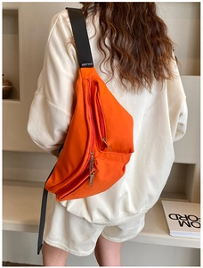 Detail of orange nylon crossbody bag with adjustable wide strap and multiple zippers