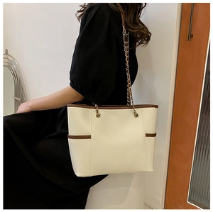 Detail of a two-tone cream and brown tote bag featuring side pockets and a chain strap