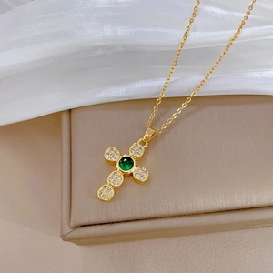 Detail of cross pendant with green gemstone and white pavé zircons on gold chain