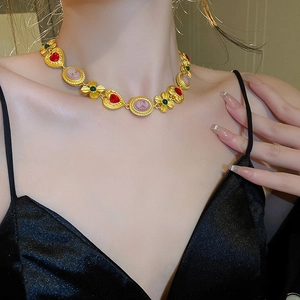 Primer plano de collar vintage dorado con gemas de corazón rojo y colgantes de camafeo