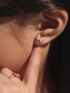 Detail of pink butterfly enamel gold earrings and ring set worn by a child model