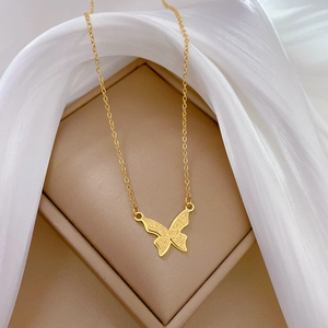Détail d'un pendentif papillon mat sur un collier en acier titane doré pour femme