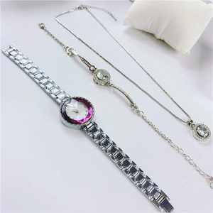 Detailed shot of silver watch and jewelry set with a purple gradient dial and crystals