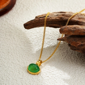 18K gold necklace featuring an oval green emerald pendant on a vintage wood branch