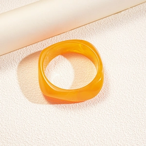 Macro view of wide translucent orange resin geometric square bangle with marbled texture
