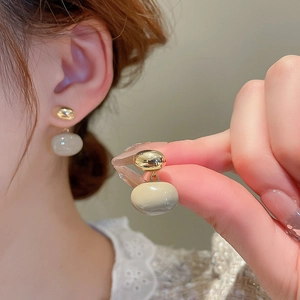 Boucles d'oreilles irrégulières plaquées or avec perles en émail beige sur modèle