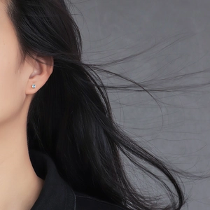 Elegant gold square earrings with blue zircon gemstone on a model's ear
