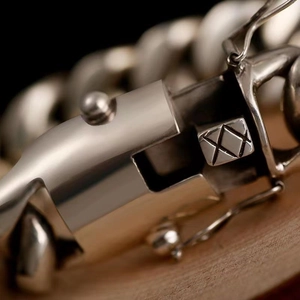 Bracelet chaîne argentée de style punk avec fermoir métallique sur fond de bois sombre